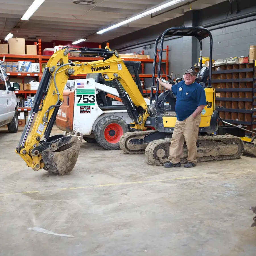 Plumber standing in front of an excavator