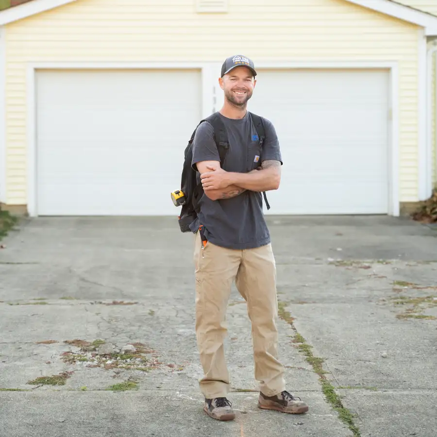 Plumber with tools standing in front of a house