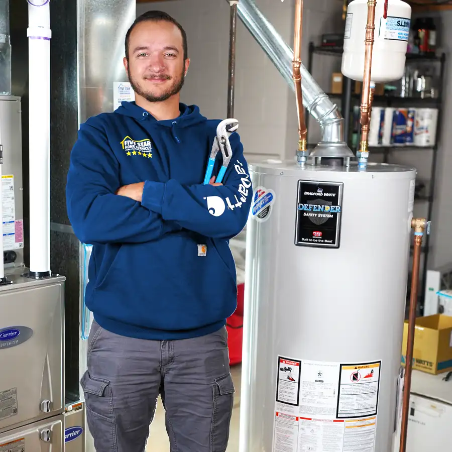 Plumber holding a wrench next to a water heater.