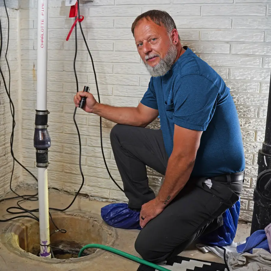 Plumber holding a flash light working on a sump pump