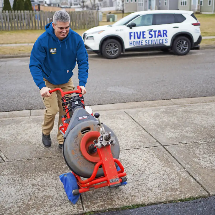 plumber walking with plumbing equipment with a five star home services truck in the background