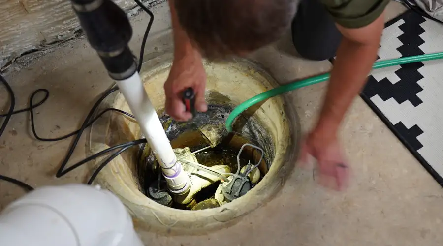 Close up of a plumber holding a flashlight inspecting a sump pump