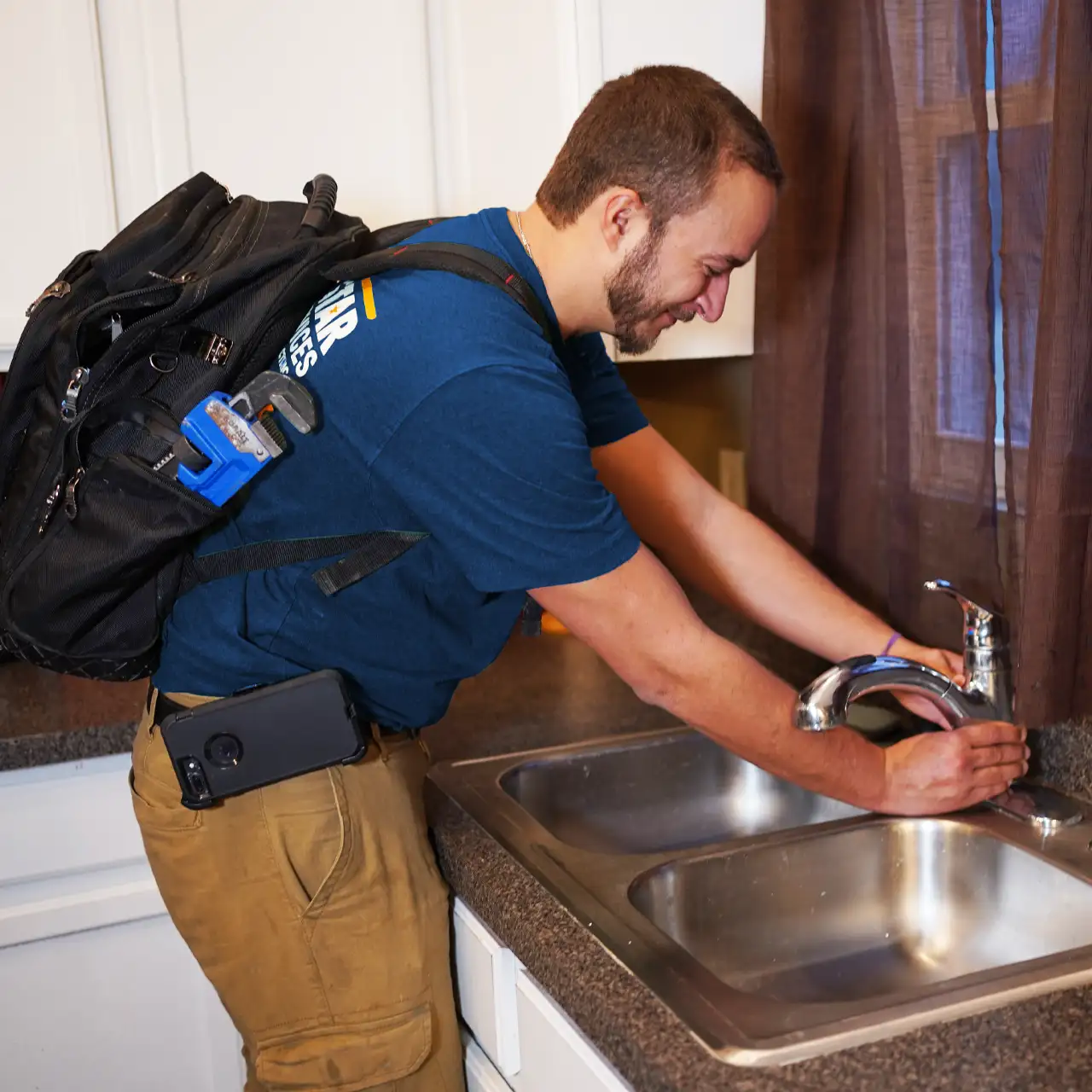 Plumber fixing a sink with a backpack on